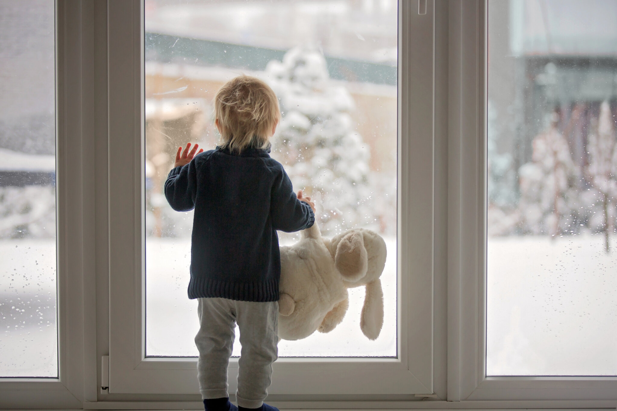 Look it is snowing. Ребенок у окна зимой. Зимнее окно для детей. Ребенок на подоконнике зимой. Зима за окном для детей.