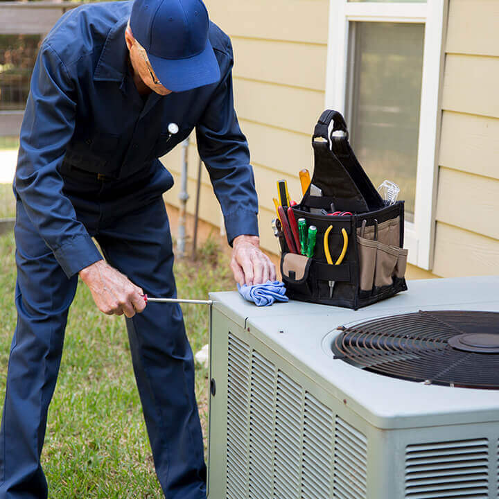 technician servicing heat pump outside of home