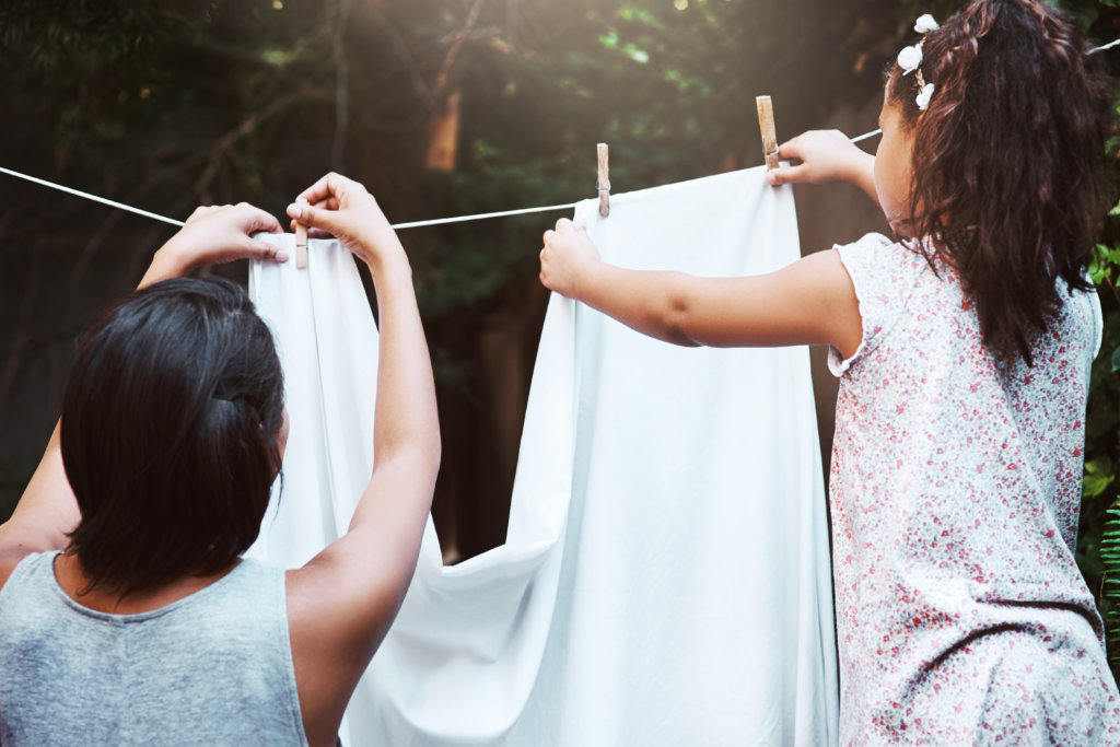 Shot of a mother and her little daughter hanging up laundry on a washing line outdoors