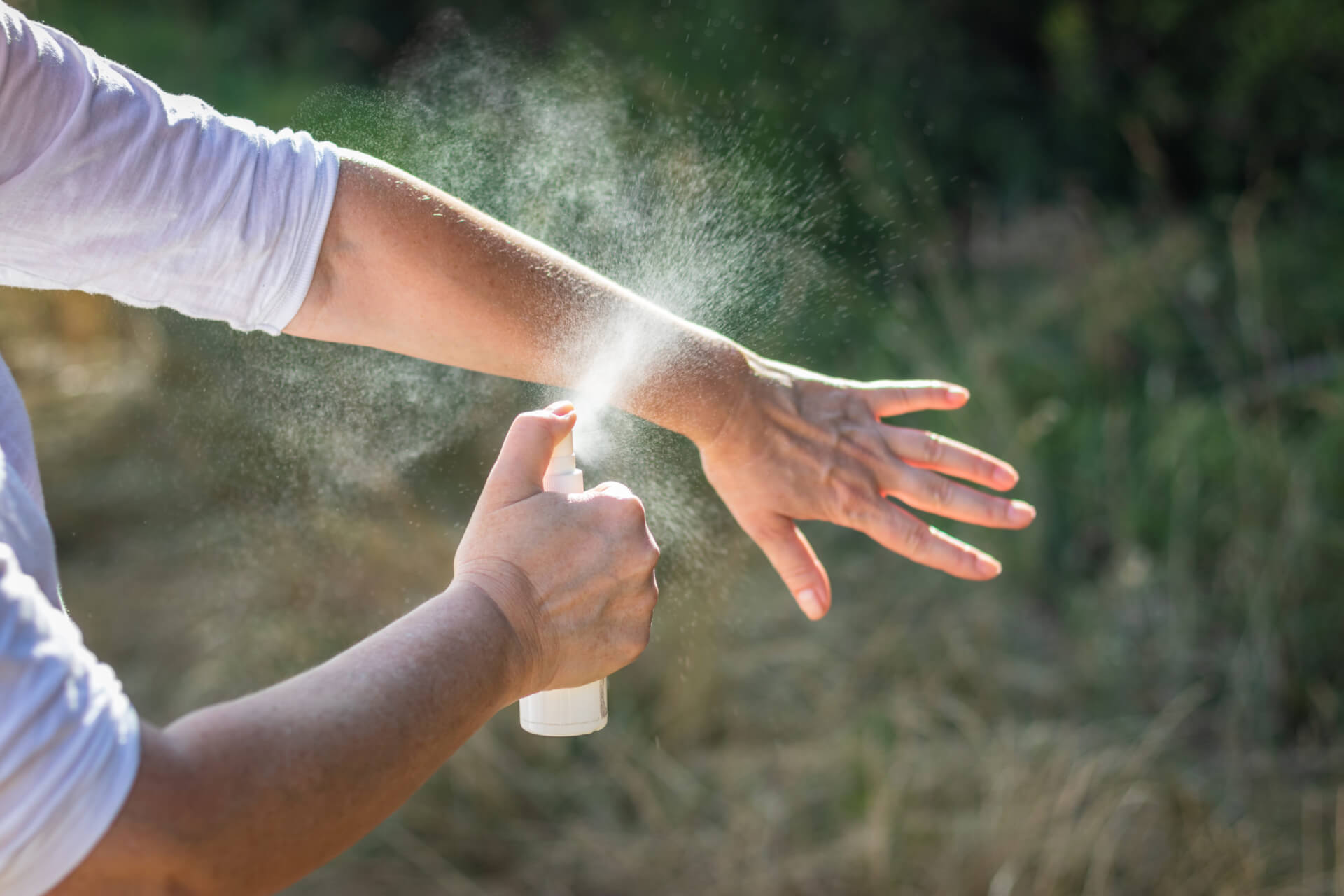 woman spraying mosquito repellent on hand